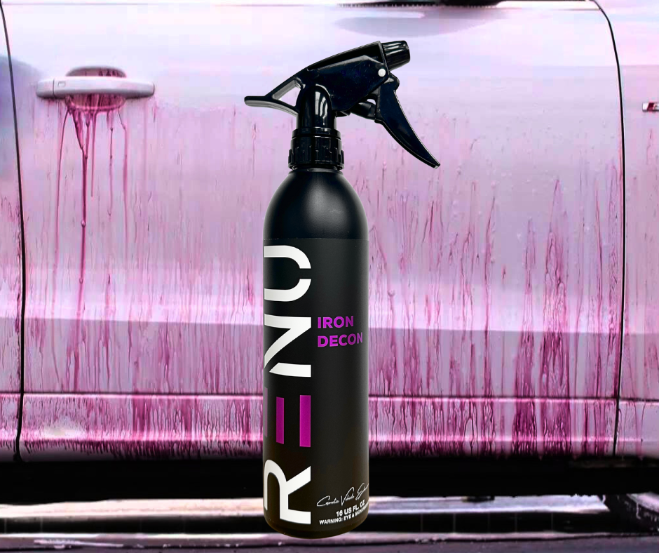 Black spray bottle labeled Iron Decon standing in front of a car door stained with pink and purple chemical residue drip marks.