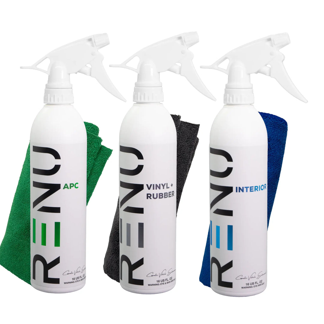 Three spray bottles labeled RENO Interior Clean & Protect with microfiber cloths in green, black, and blue colors behind each bottle.