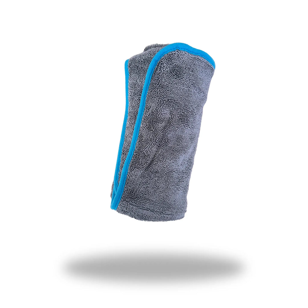 Twist 'n Dry Drying Towel rolled up, gray microfiber with blue trim, isolated on white background.